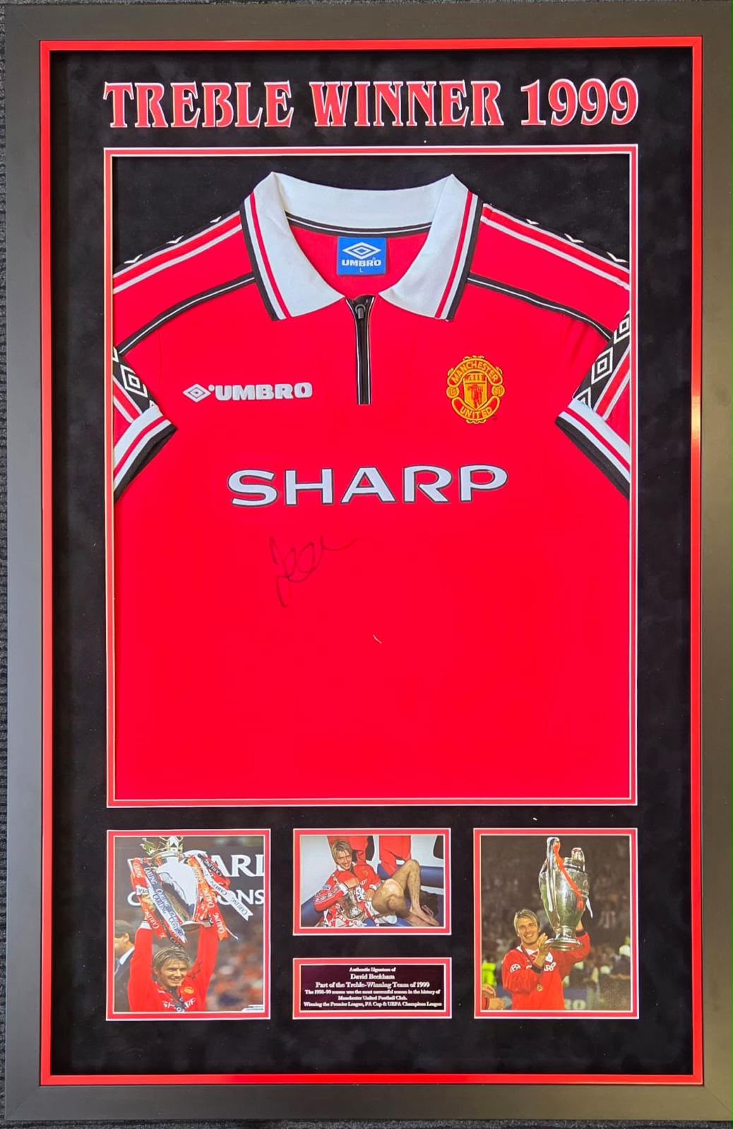 Premium framed display containing a hand-signed Manchester United 1999 treble winners shirt by Sir David Beckham with commemorative imagery.