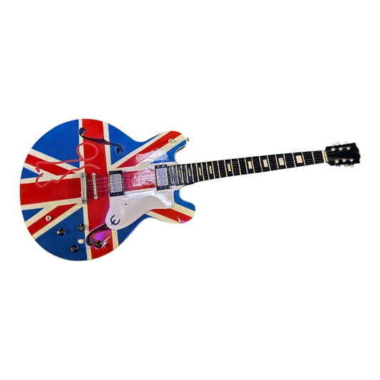 A high-resolution photo of an authentic Noel Gallagher signed union jack guitar, featuring the iconic British flag design with a bold, hand-signed autograph by the Oasis songwriter on the body.
