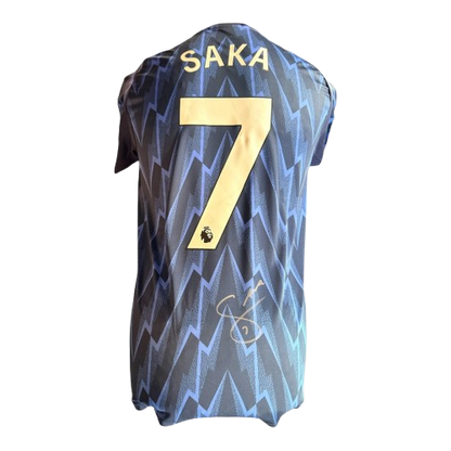 Close-up detail of Bukayo Saka's authentic signature on the 2025/26 blue Arsenal away jersey.