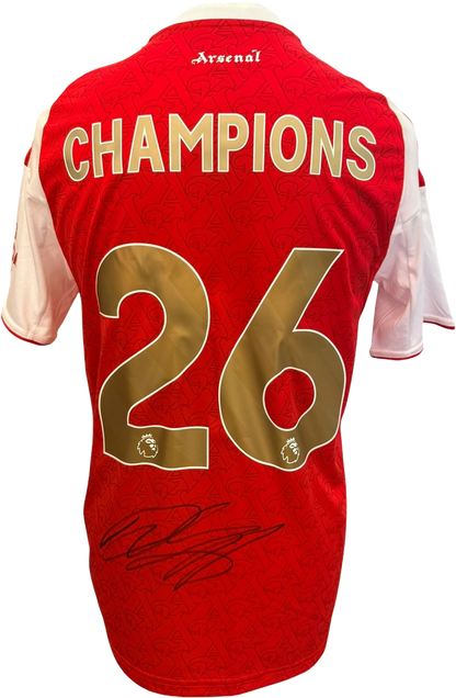 The reverse of the 2025/26 Arsenal home jersey showcasing the commemorative gold Champions printing and Declan Rice's hand-signed autograph on the fabric.