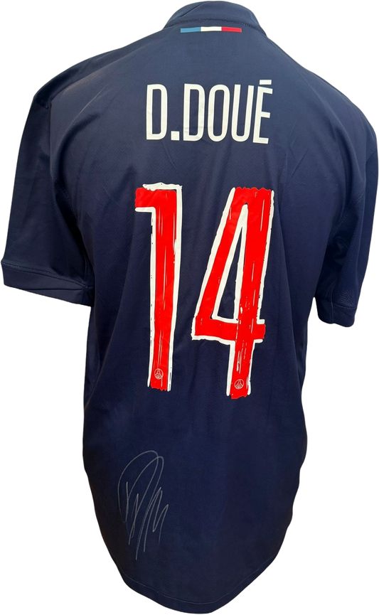 The reverse of the blue PSG shirt showing Desire Doue's name and number alongside his clear hand-signed autograph in black marker.