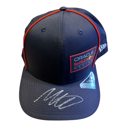 Detailed 45-degree top-down view of a genuine Max Verstappen autograph on the official navy Oracle Red Bull Racing team cap.