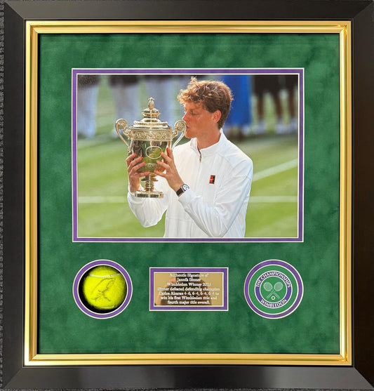 Front view of a 3D shadow-box frame featuring a hand-signed Jannik Sinner tennis ball mounted against a green background alongside a Wimbledon trophy photo and engraved plaque.
