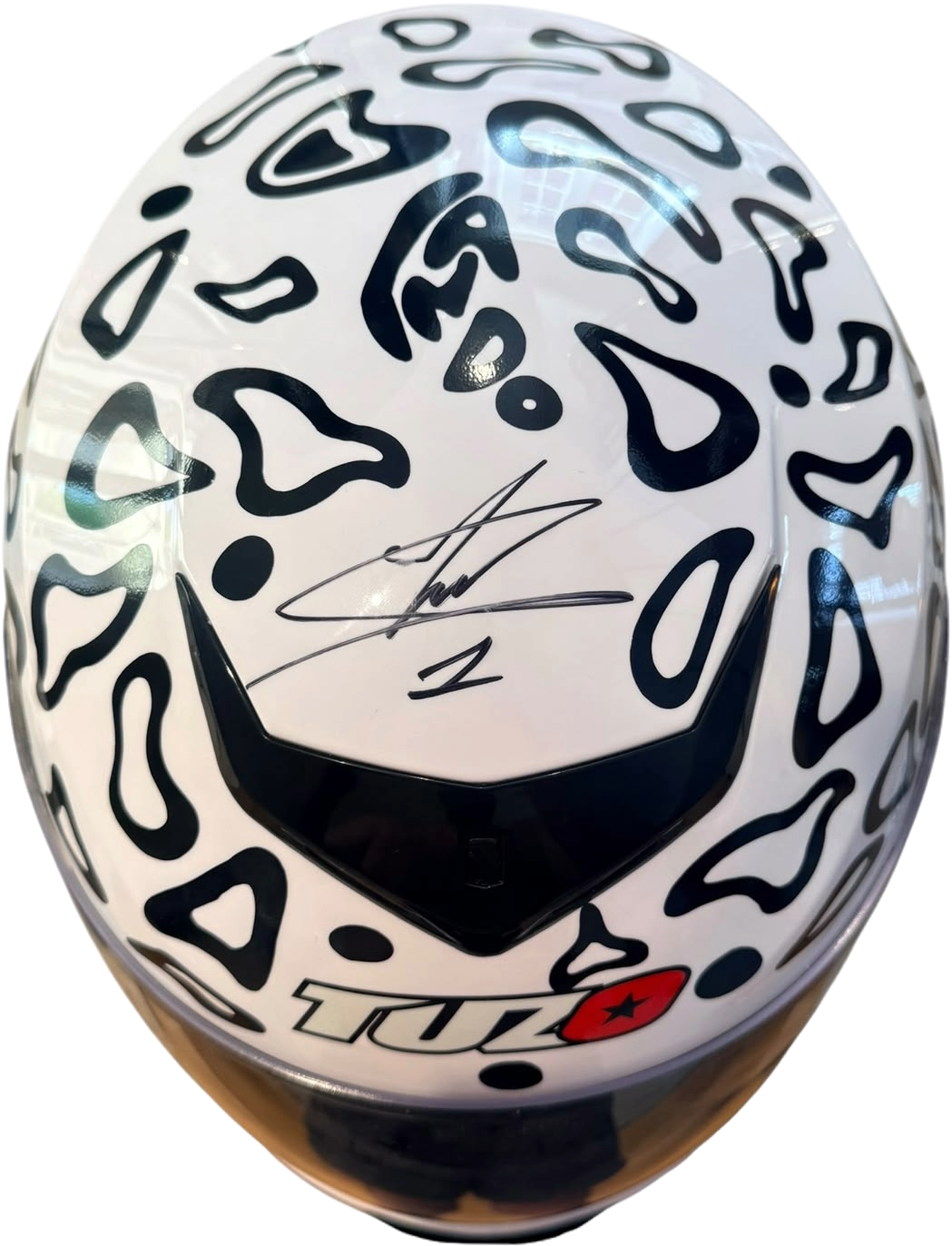 Top-down view of a full-size replica Lando Norris racing helmet showing the autograph on the crown, displayed alongside the Certificate of Authenticity.