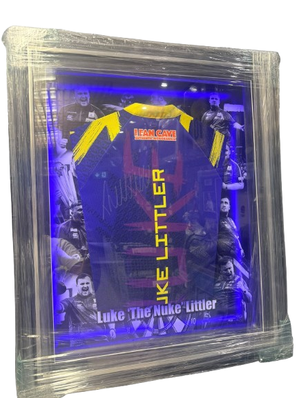 A bespoke framed Luke Littler signed darts shirt featuring a silver signature and a high-resolution action photo montage background.