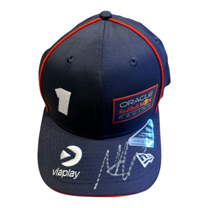 A 45-degree display shot of a Max Verstappen signed Red Bull cap, highlighting the authentic driver branding and unique signature.