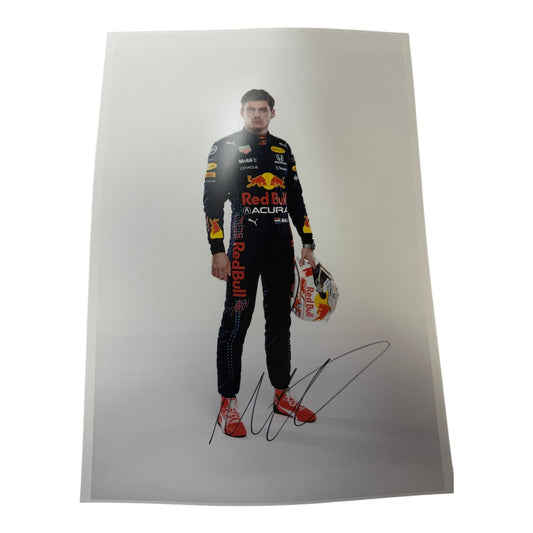 A professional studio photograph of Max Verstappen in his Red Bull Racing uniform, holding his helmet, hand-signed in bold silver ink with a Certificate of Authenticity.