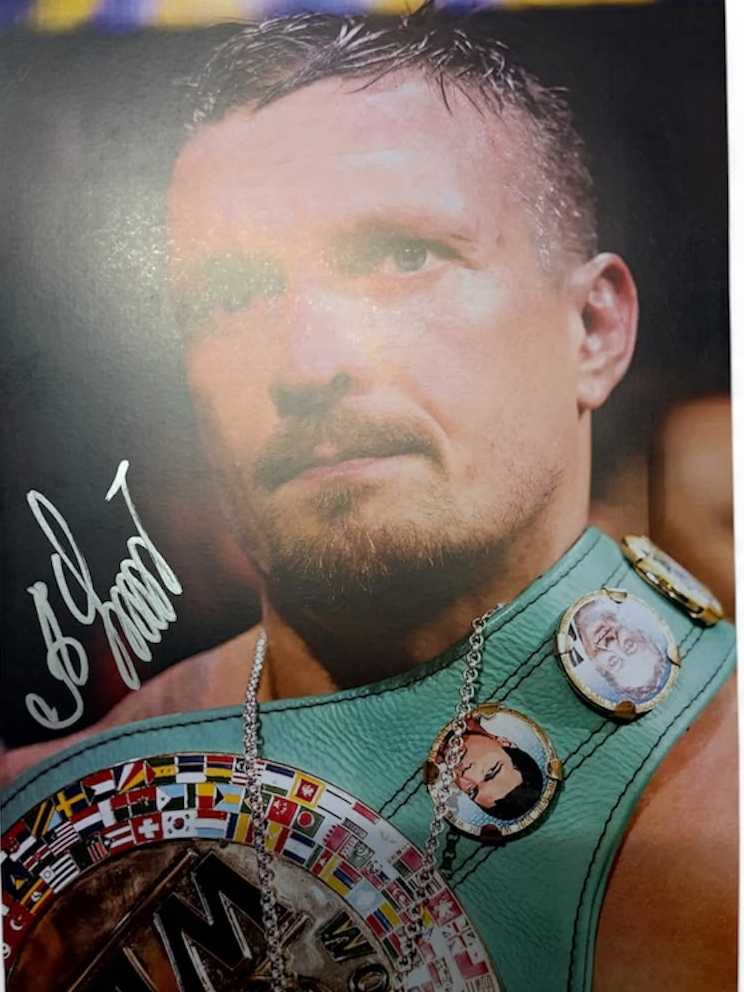 Signed Oleksandr Usyk photo celebrating with the WBC world heavyweight championship belt, featuring a bold hand-signed autograph across the image