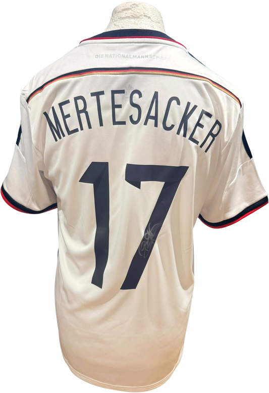 Rear view of a replica 2014 Germany home shirt hand-signed on the back by defender Per Mertesacker, displayed alongside the Certificate of Authenticity.