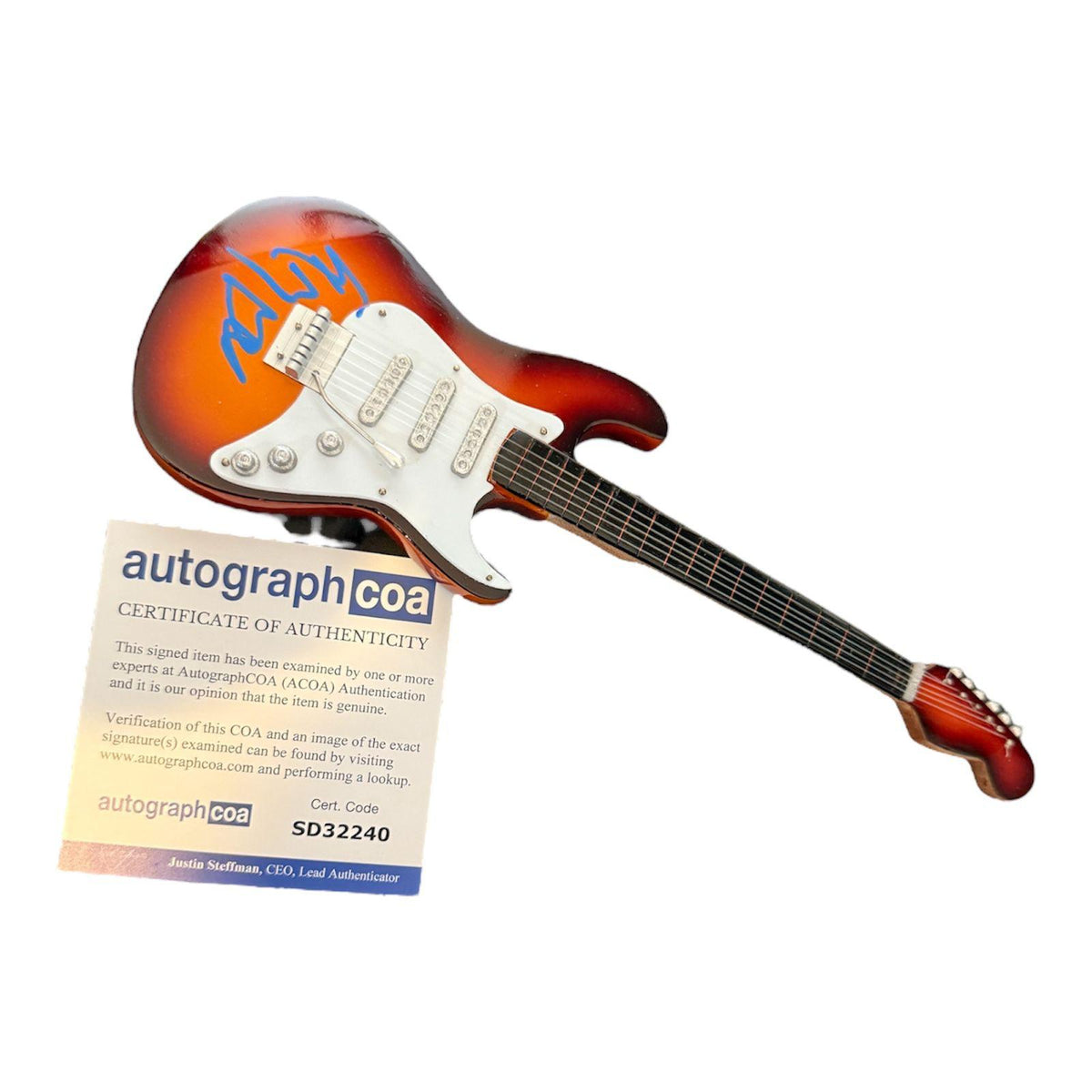Front view of an auburn coloured miniature guitar boldly signed by Post Malone in blue pen, displayed alongside its Certificate of Authenticity.