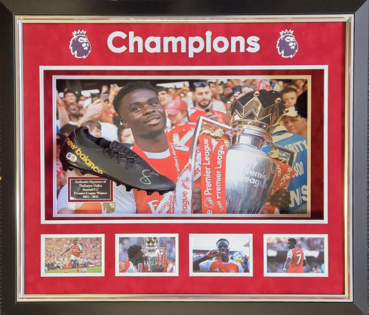 A premium three-dimensional framed display featuring a hand-signed Bukayo Saka football boot alongside a title-winning photo montage, a bespoke plaque, and Champions emblazoned across the top.
