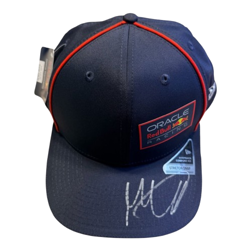 Top-down 45-degree view of a signed Max Verstappen navy Red Bull cap showcasing the unique hand-signed autograph on the brim.