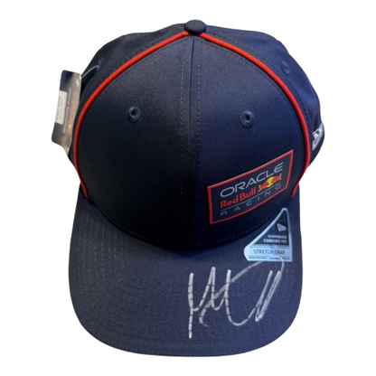 Top-down 45-degree view of a signed Max Verstappen navy Red Bull cap showcasing the unique hand-signed autograph on the brim.