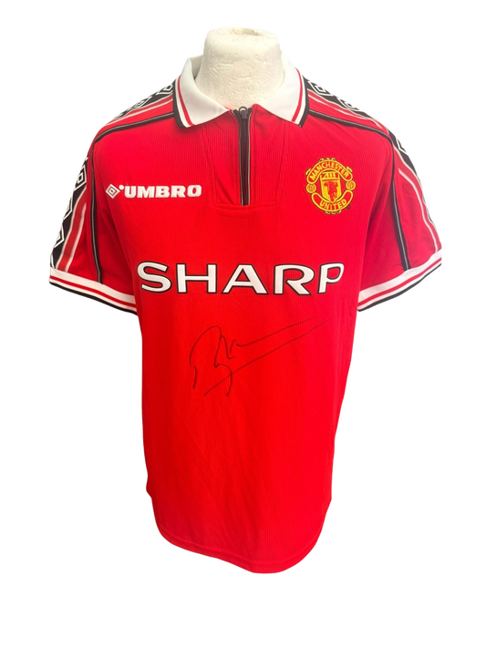 Front view of a red 1998/99 Manchester United home shirt featuring a large signature in black permanent marker by Roy Keane.