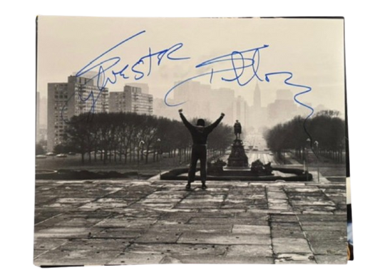 A hand-signed Sylvester Stallone photograph of Rocky Balboa standing at the top of the Philadelphia Museum of Art steps with arms raised.